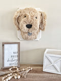 A plush Puppy Dog Wall Mount handmade by ClaraLoo in an animal themed nursery. This stuffed dog is made with soft tan faux fur and crocheted accents. This plush puppy is mounted on a white wooden plaque.