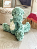 A green plush T-Rex stuffed animal made by ClaraLoo with crocheted accents in a dinosaur themed nursery.
