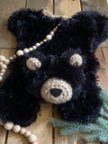 A plush black bear lovey made by ClaraLoo with crocheted accents.