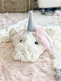A plush unicorn rug made by ClaraLoo on the floor of a fantasy themed nursery. The unicorn rug features ultra soft fabric with a crocheted horn and ears.